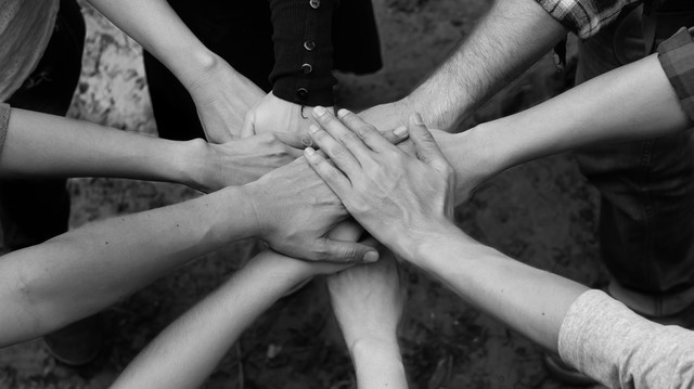 A diverse team placing their hands together